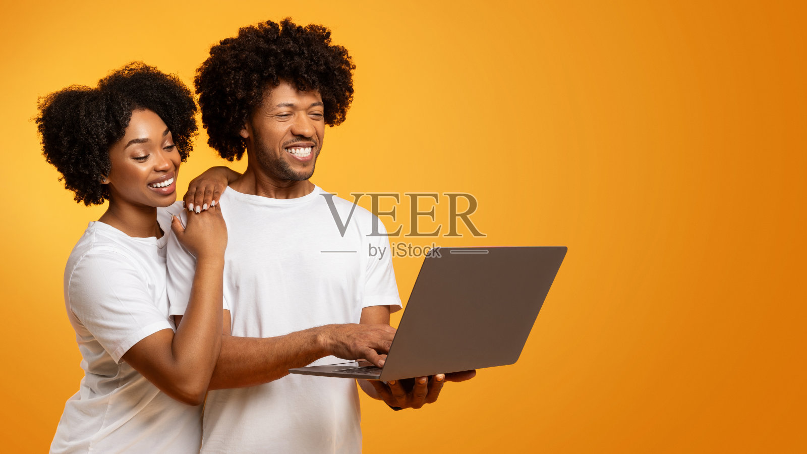 阳性非裔美国夫妇一起使用笔记本电脑在橙色照片摄影图片