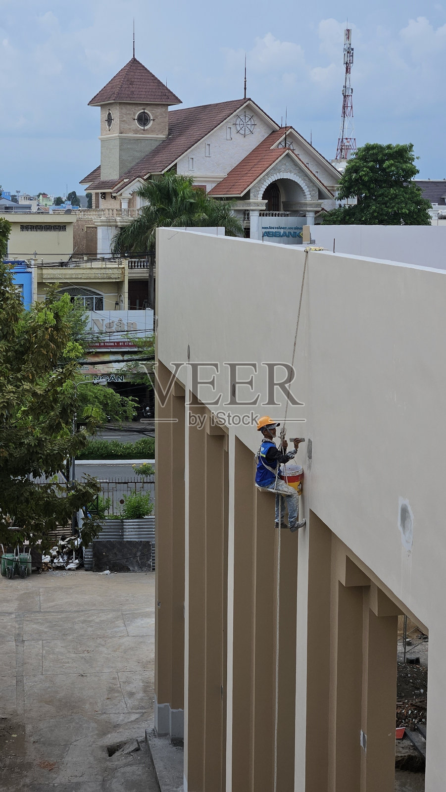 建筑工人正在绳子上荡来荡去粉刷墙壁。正在建设中。照片摄影图片