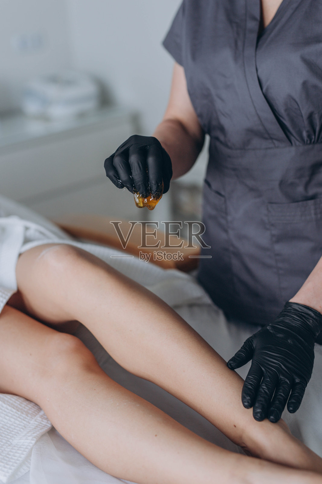 美容师在水疗中心用液体糖为年轻女子脱毛照片摄影图片