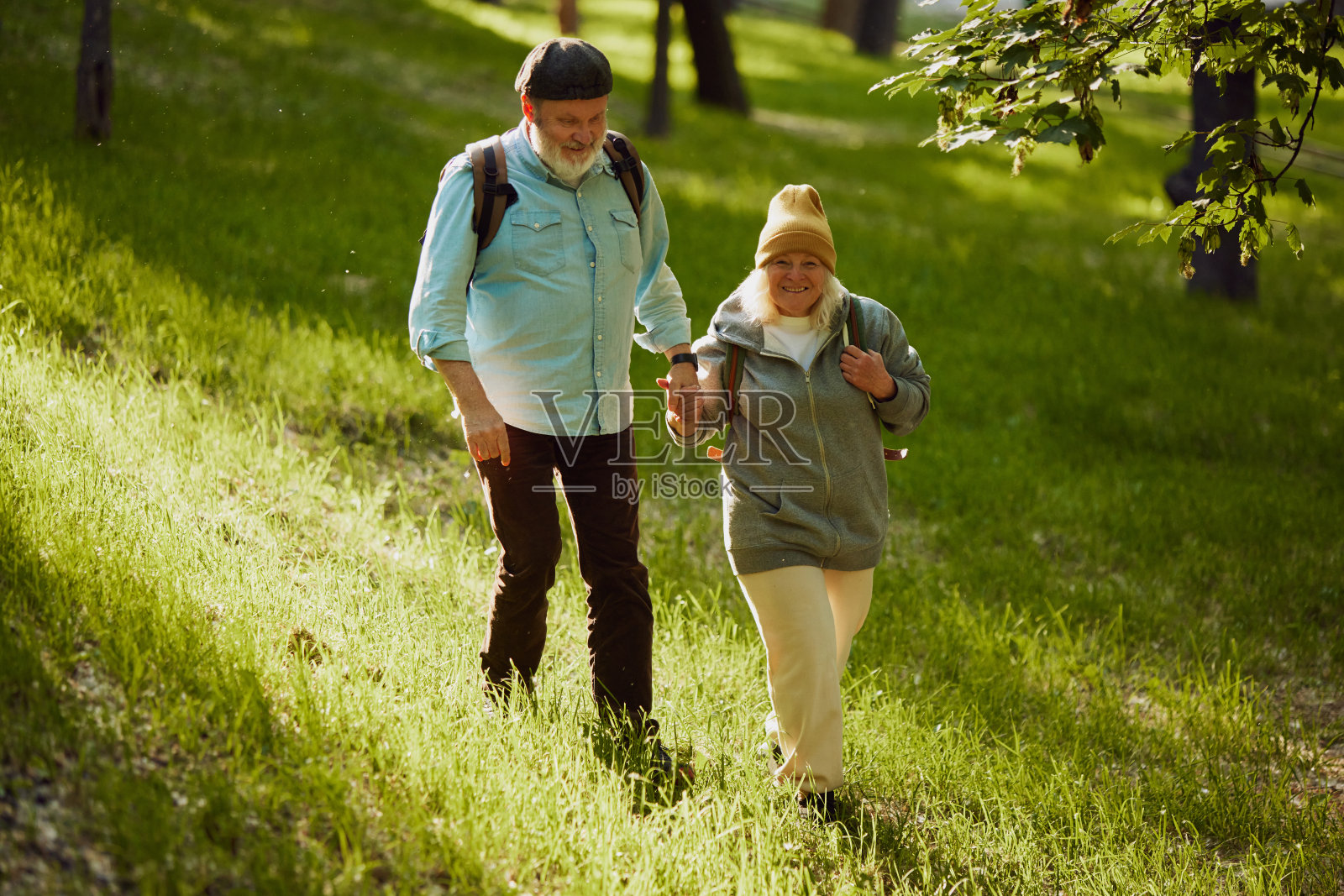 老年夫妇在郁郁葱葱的公园里徒步旅行，穿着休闲舒适的衣服，分享户外冒险的快乐时刻。照片摄影图片