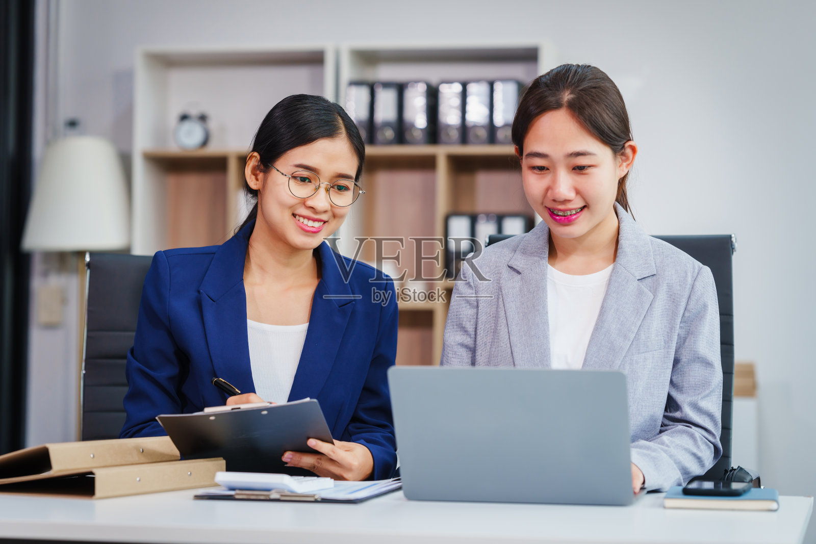 两位亚洲女企业家在股票市场策略和金融服务方面合作，就贷款申请和投资机会交换意见和建议。照片摄影图片