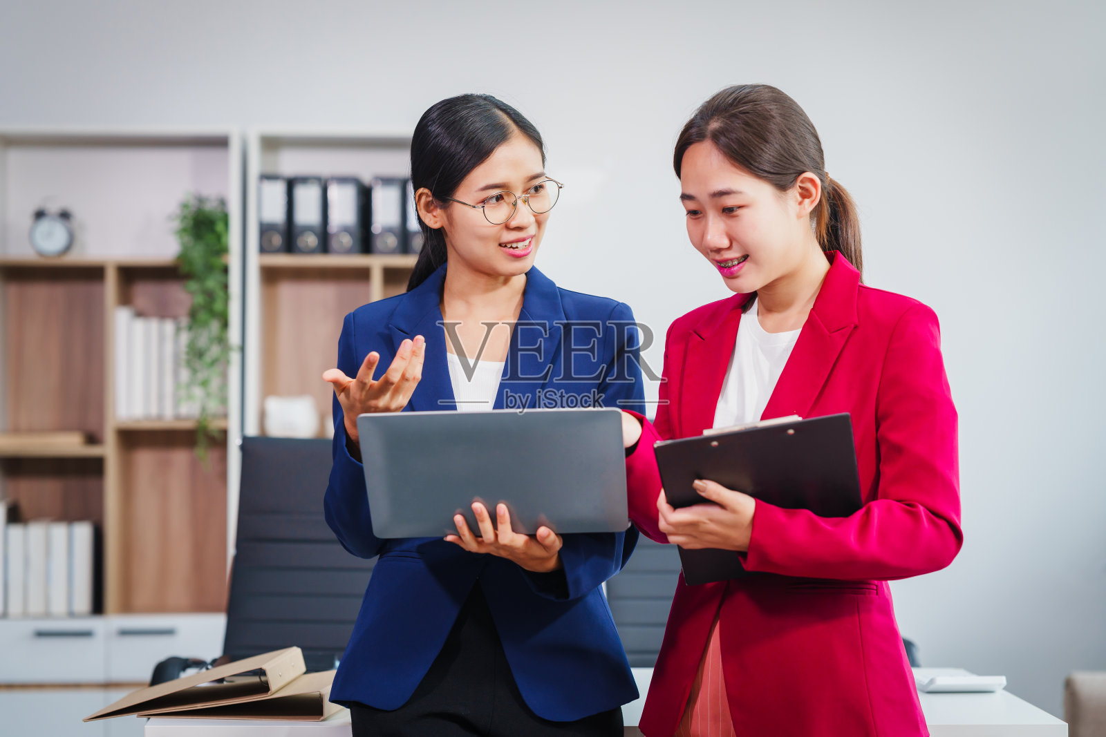 两位亚洲女企业家在股票市场策略和金融服务方面合作，就贷款申请和投资机会交换意见和建议。照片摄影图片