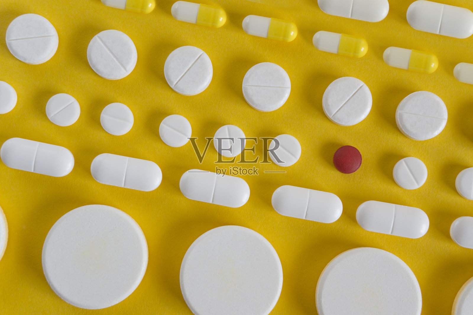 黄色背景上一排排白色药丸照片摄影图片