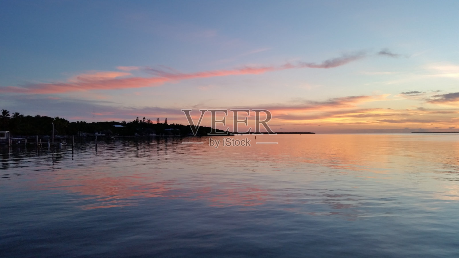 佛罗里达伊斯拉莫拉达海湾宁静的水面上反射着多彩的日落。照片摄影图片