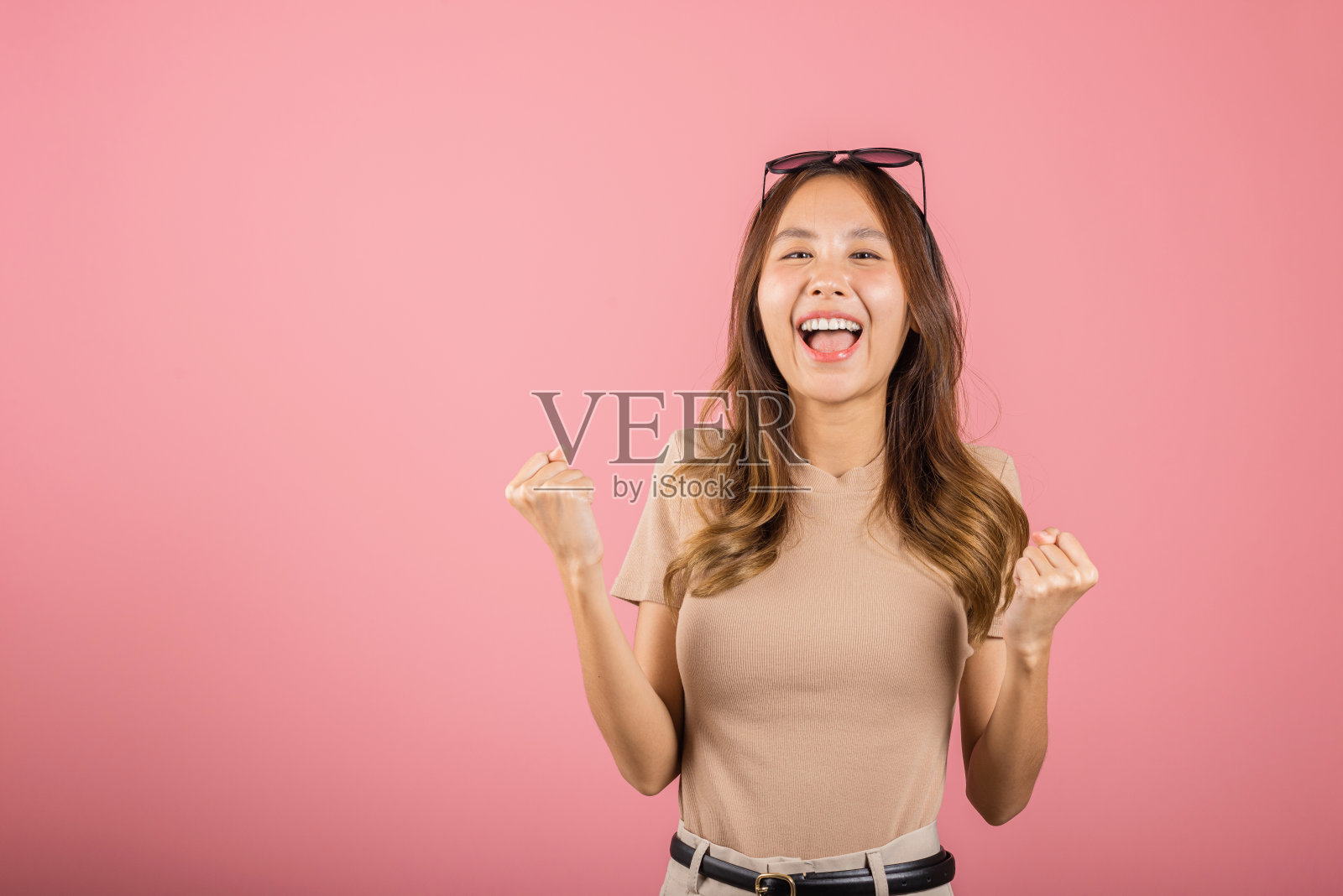 戴眼镜的年轻女子举手庆祝她的胜利照片摄影图片