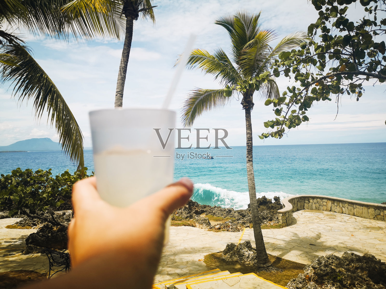 手拿柠檬水，俯瞰大海和棕榈树照片摄影图片