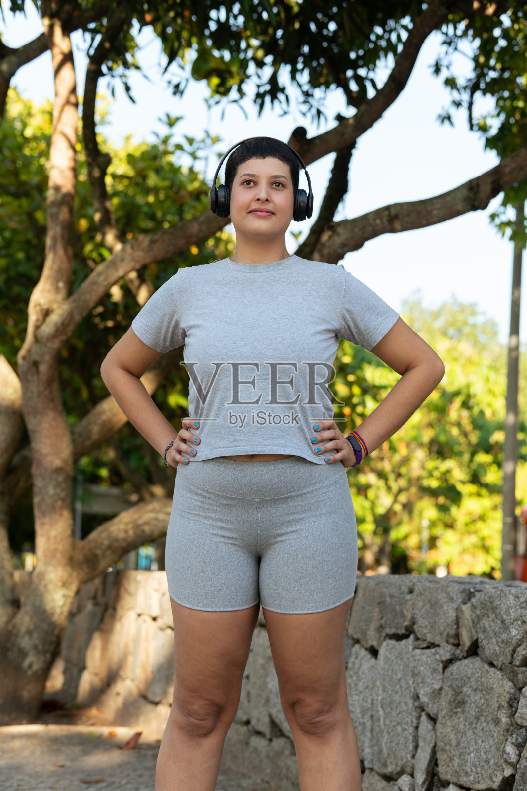 年轻女子一边做体育锻炼，一边在户外散步和跑步，戴着耳机听音乐照片摄影图片