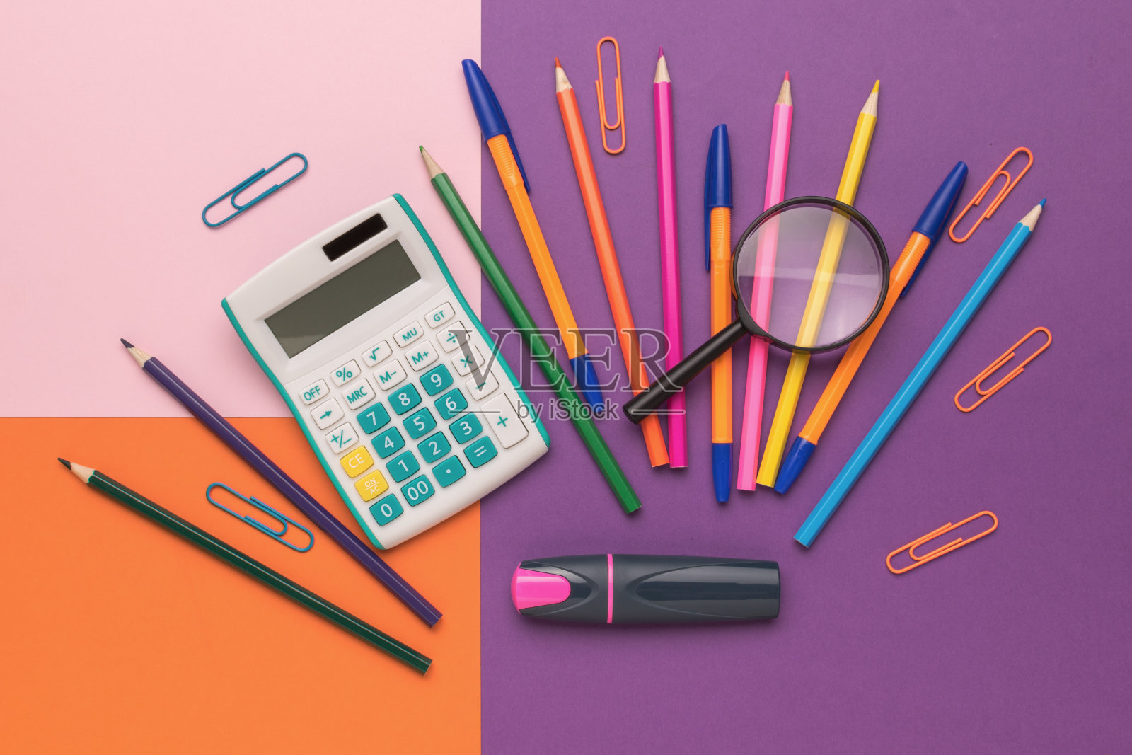 五颜六色的办公用品在一个充满活力的彩色背景与计算器和放大镜照片摄影图片