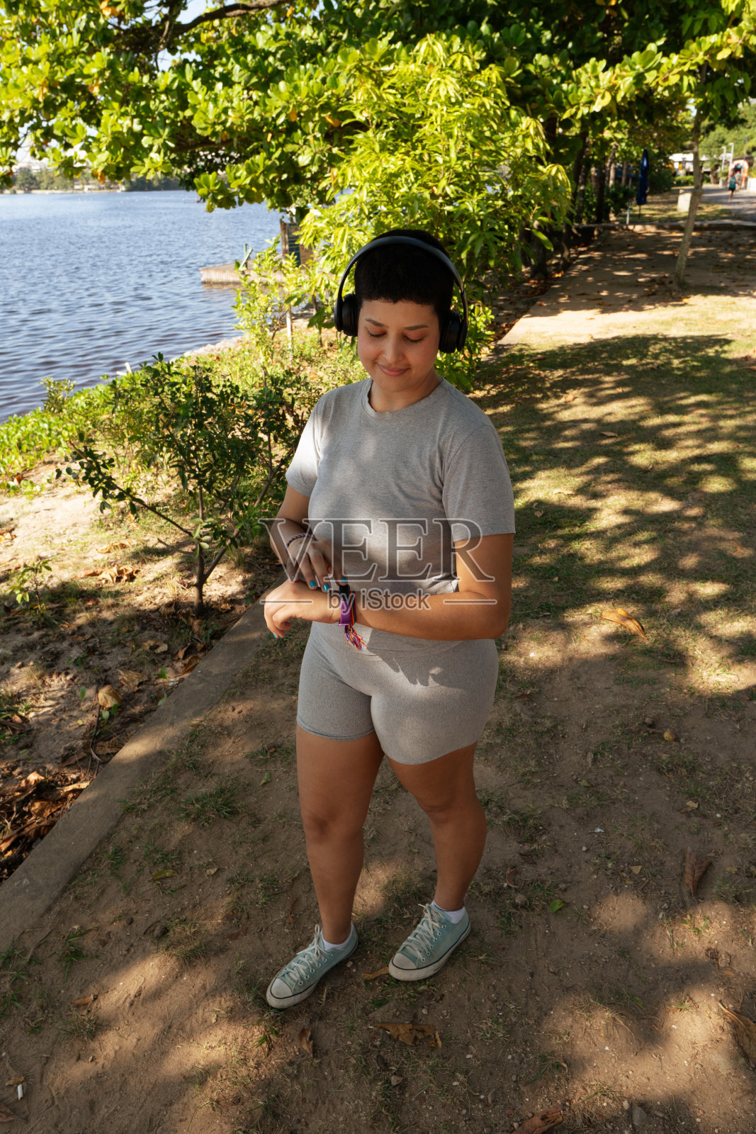 年轻女子一边做体育锻炼，一边在户外散步和跑步，戴着耳机听音乐照片摄影图片