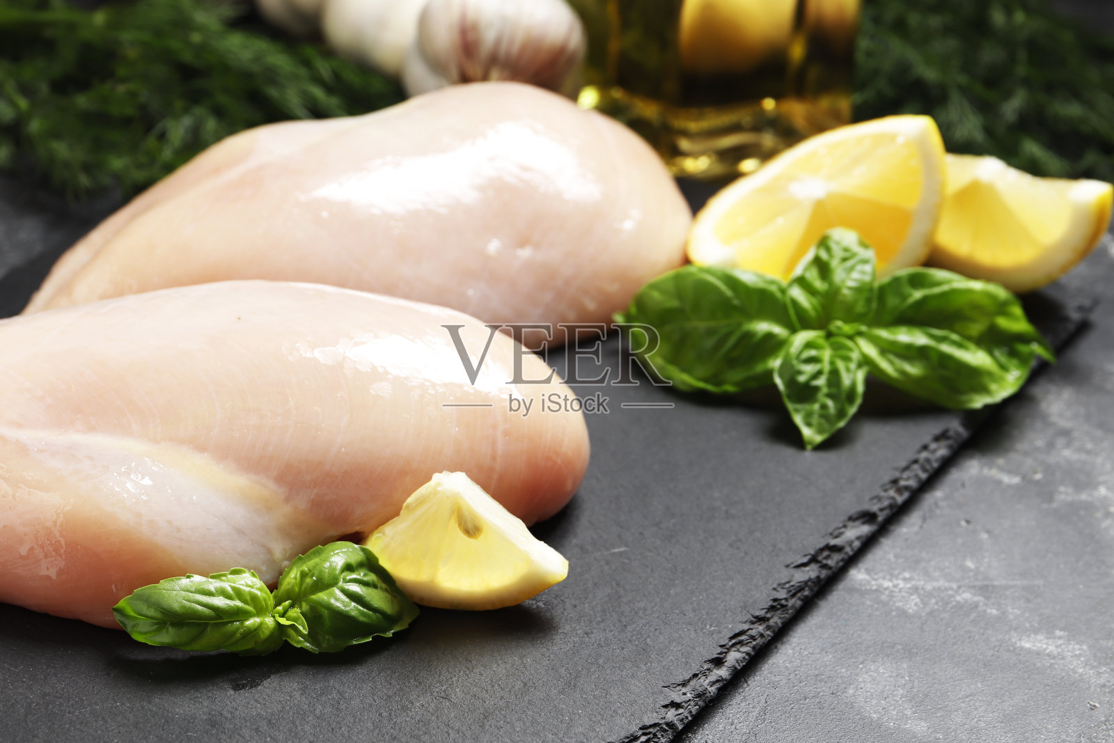 生鸡肉片与罗勒，柠檬和黄油在黑色大理石背景与文字的地方。照片摄影图片