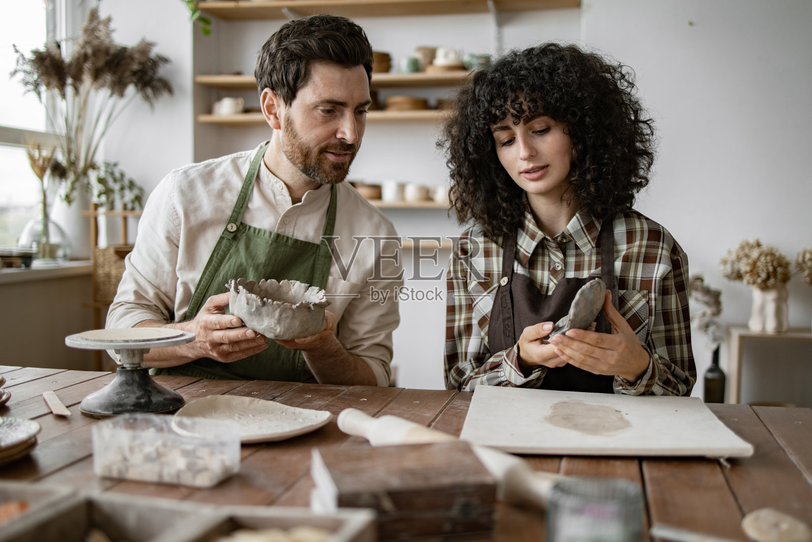大胡子男女在艺术工作室一起雕刻陶土照片摄影图片