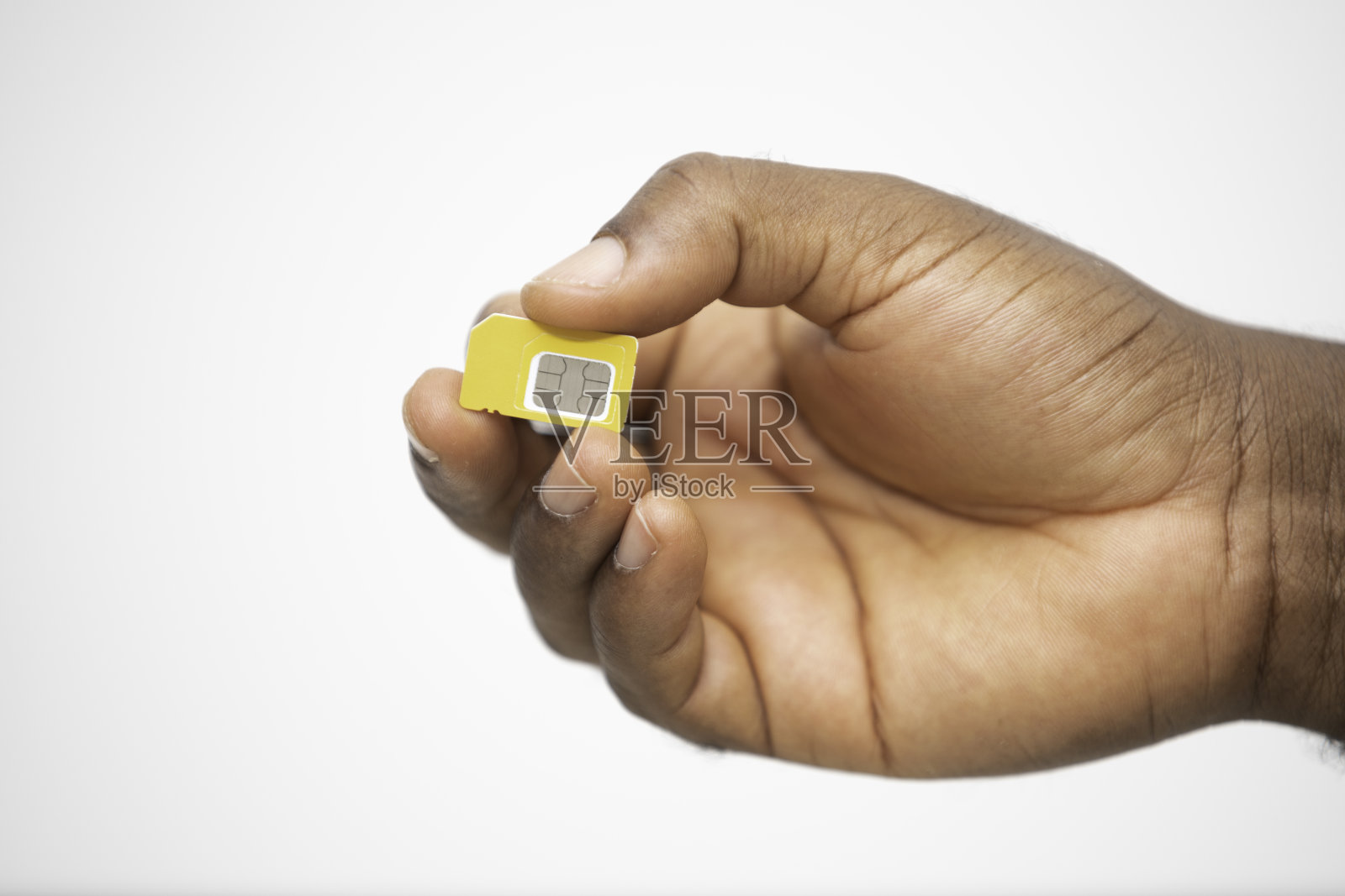 黑色的手拿着白色背景的黄色SIM卡照片摄影图片