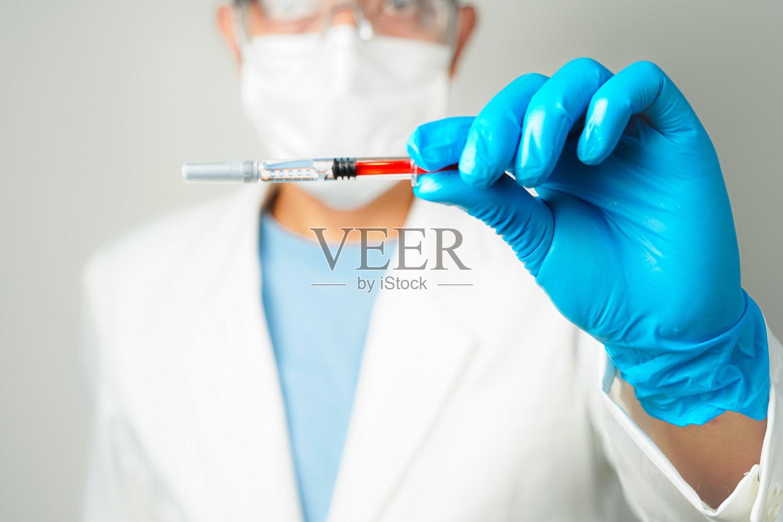 戴着蓝色手套拿着注射器的医生或科学家照片摄影图片