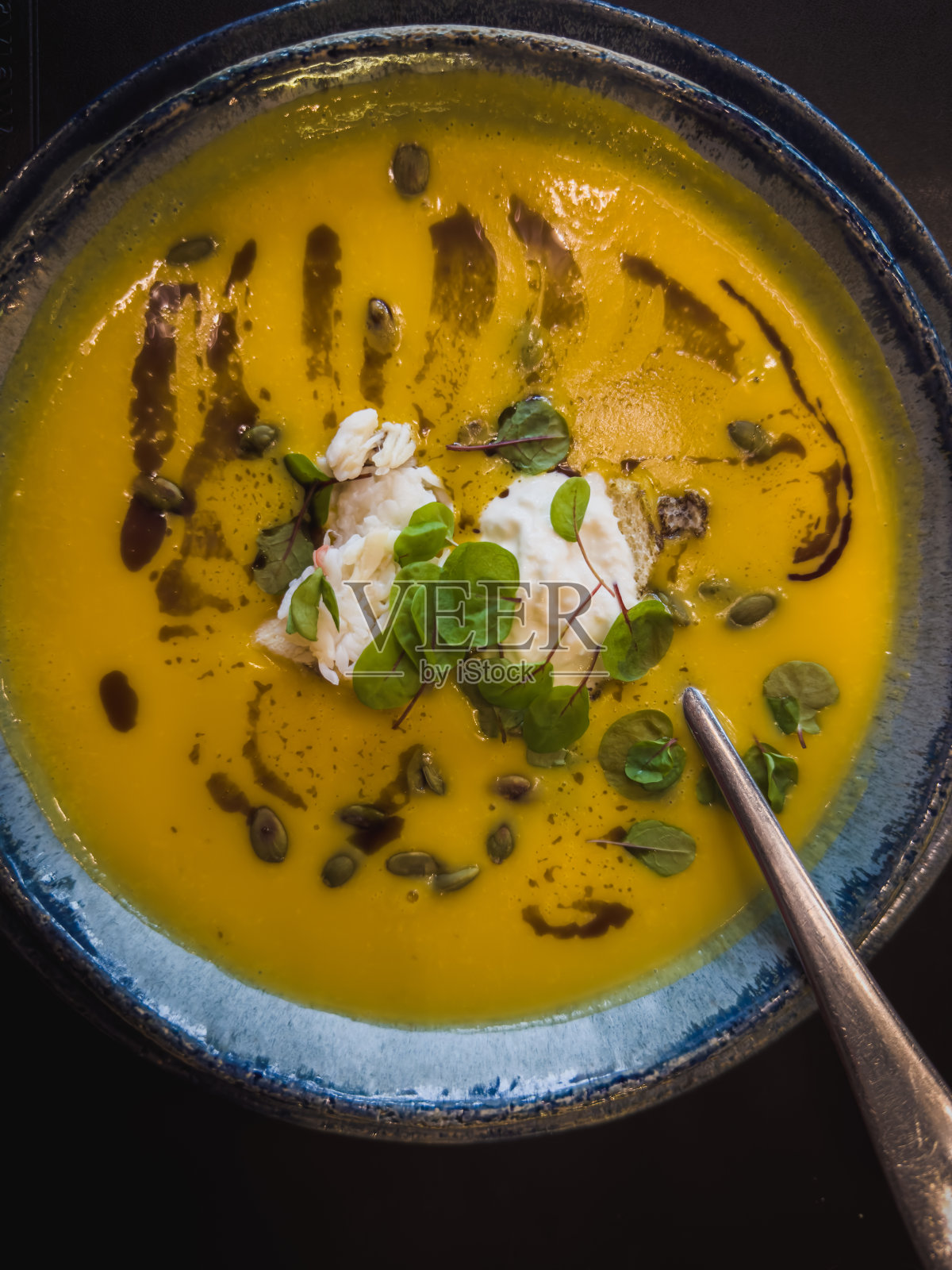 南瓜奶油汤用勺子盛在碗里照片摄影图片