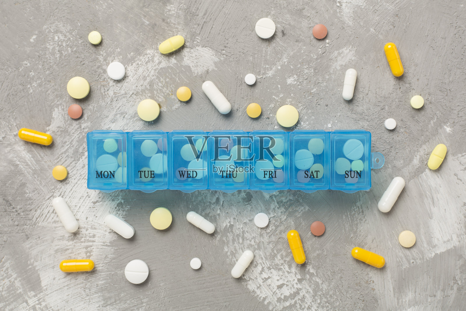 在混凝土背景上放置每日药片整理器，俯视图照片摄影图片