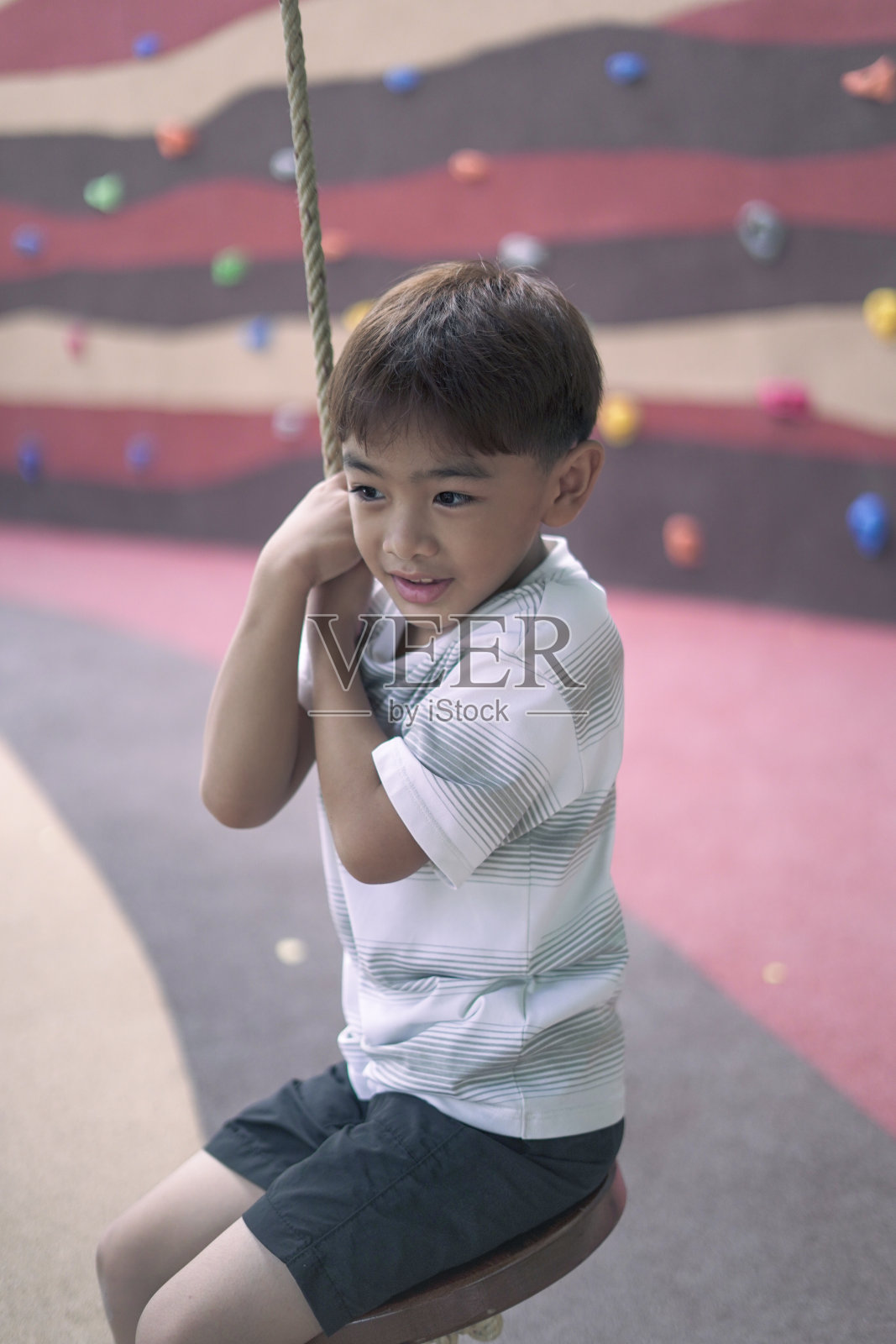 男孩坐在操场上的秋千上照片摄影图片