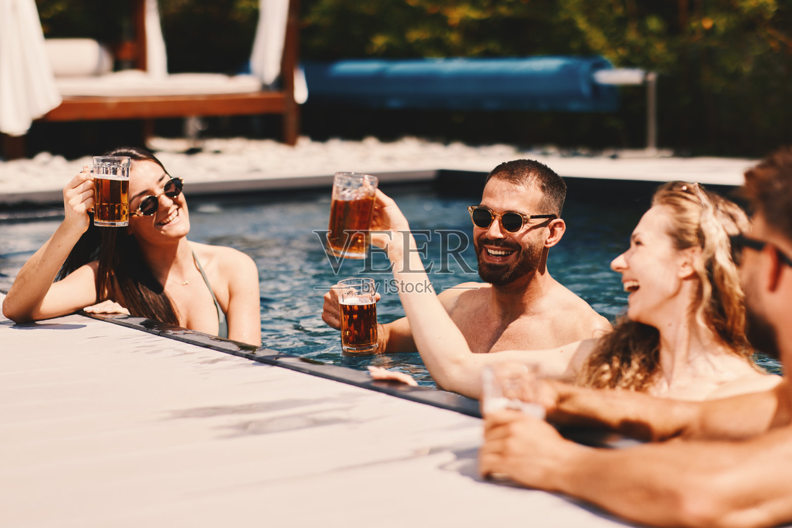 一群兴高采烈的年轻人在泳池里喝啤酒照片摄影图片