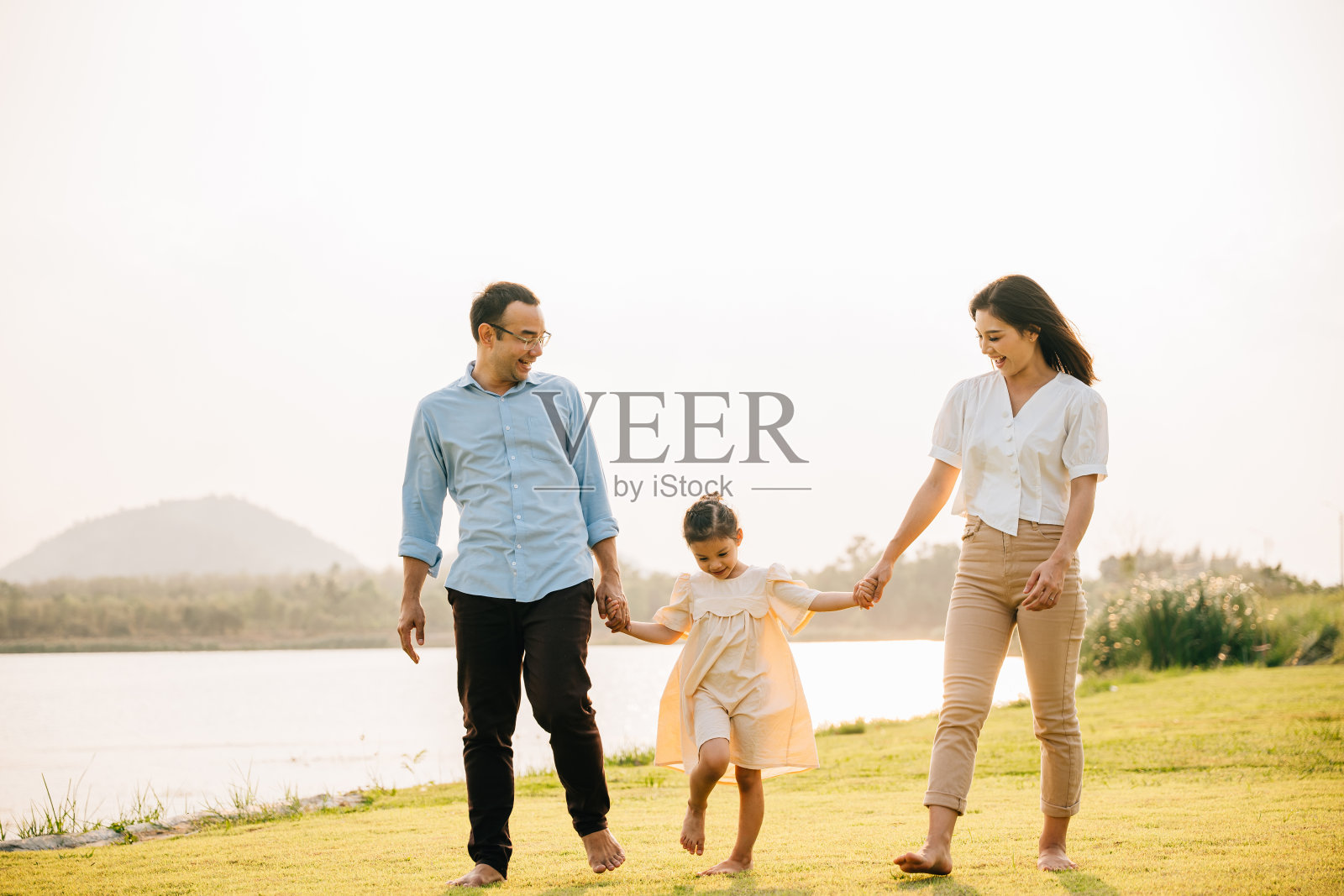 一个亚洲家庭在美丽的春天公园里手拉手散步照片摄影图片