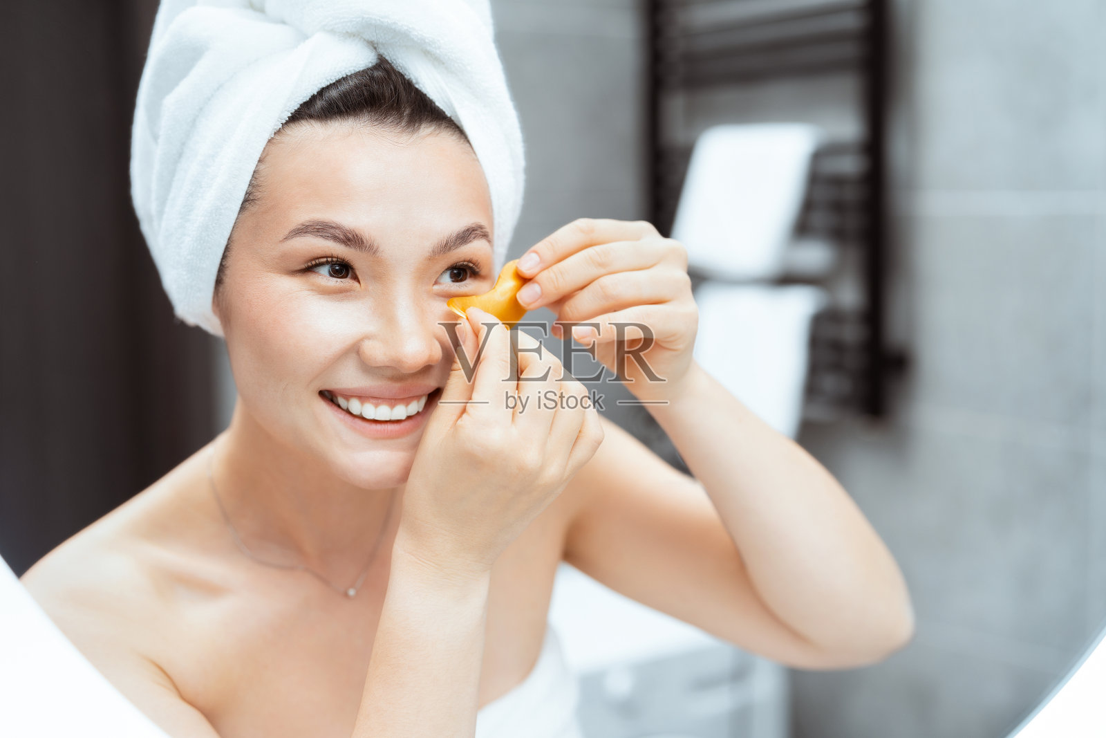 快乐的女人在现代浴室镜子里贴眼罩照片摄影图片