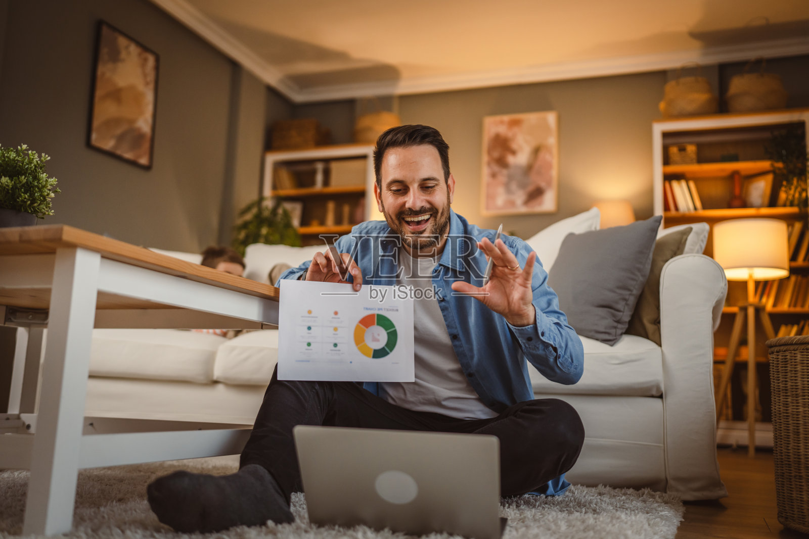 成年男子坐在家里通过视频通话与儿子在后台分享图表照片摄影图片