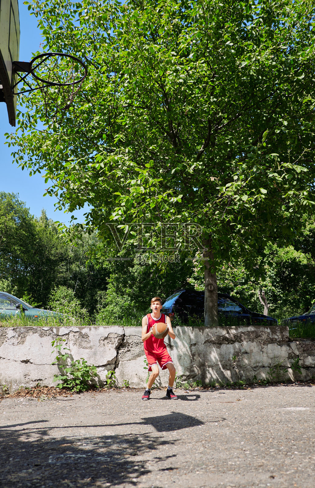 一个少年正在拳击场上进球。篮球场上的运动员。篮球运动员。运动器材。照片摄影图片