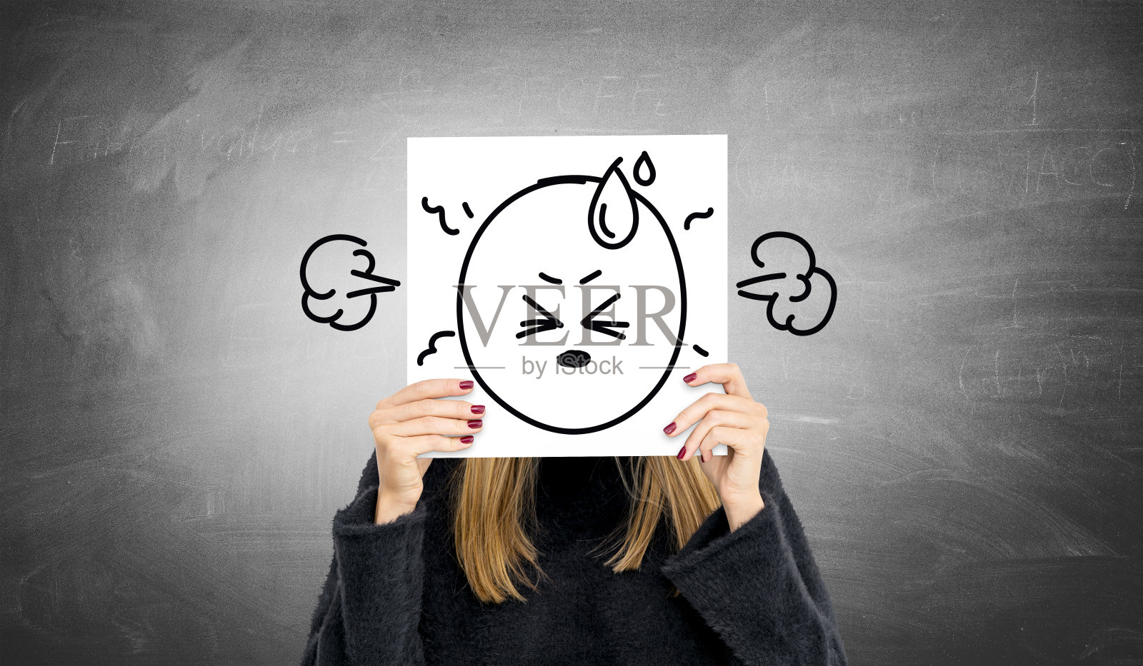 年轻女人拿着一张画着愤怒表情符号的纸照片摄影图片