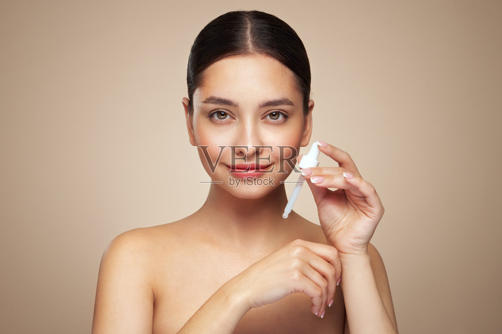 年轻漂亮的女人正在涂抹面部精华液照片摄影图片