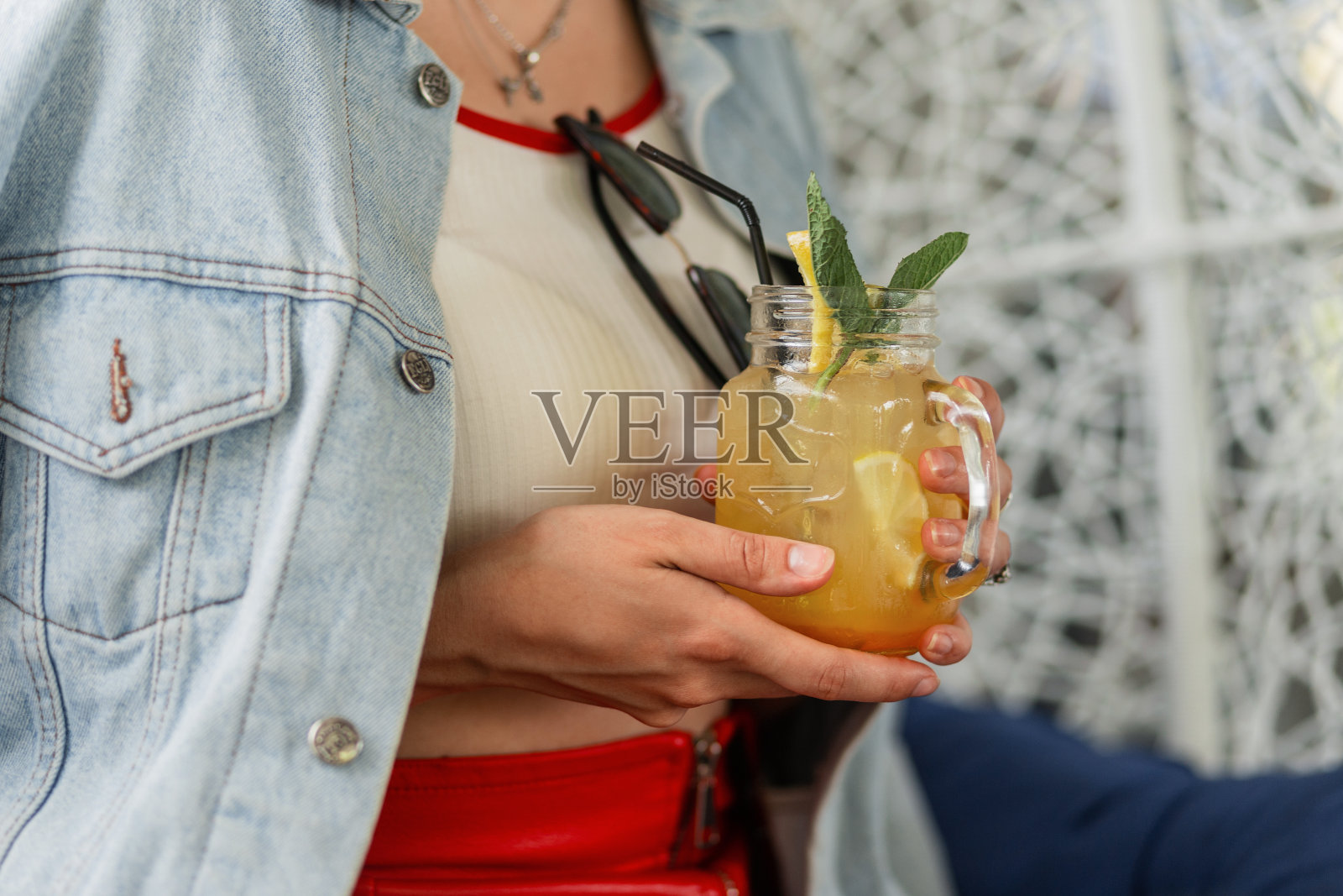 新鲜、健康、美味的柠檬水，加冰，在女性手中加叶子和薄荷。时尚的女孩拿着夏天甜美的柑橘饮料。特写镜头。照片摄影图片