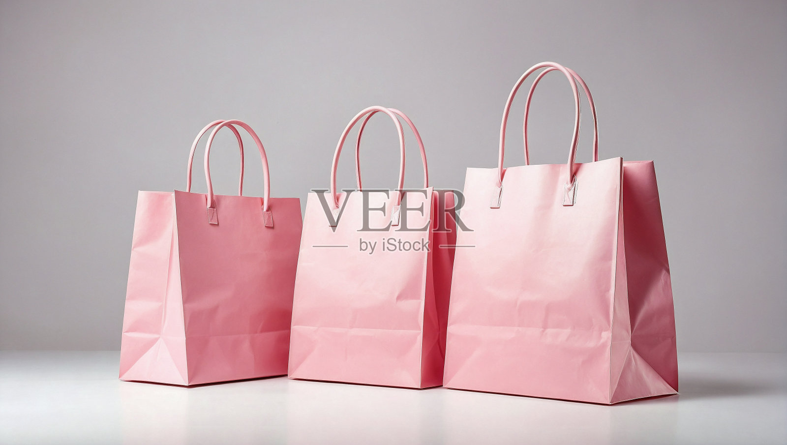 空的粉彩粉色购物袋在反光的白色表面与柔和的阴影照片摄影图片
