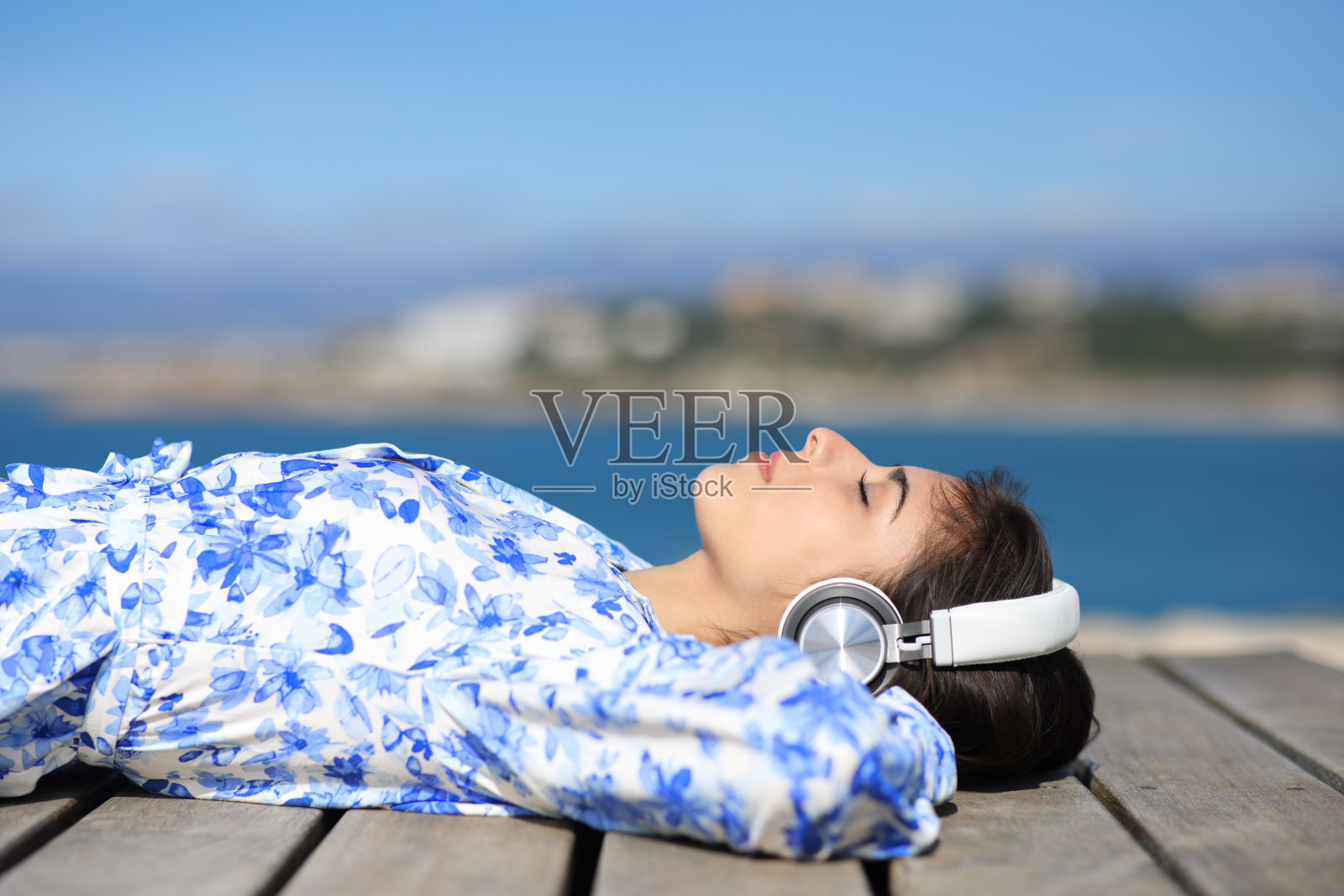 一个女人躺在沙滩上听音乐的侧面照照片摄影图片