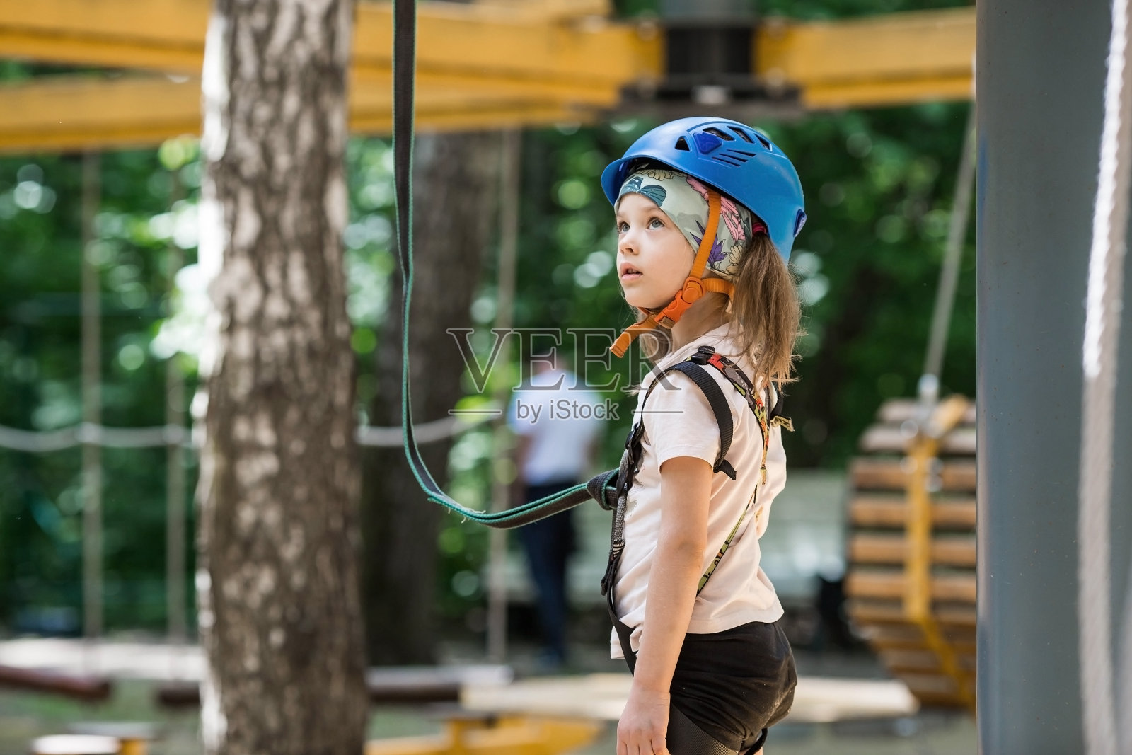 夏天。在绳索公园里，一个小孩正在爬绳桥。一个女孩在冒险公园玩得很开心。一个女孩在攀岩墙上。遵守安全法规。照片摄影图片