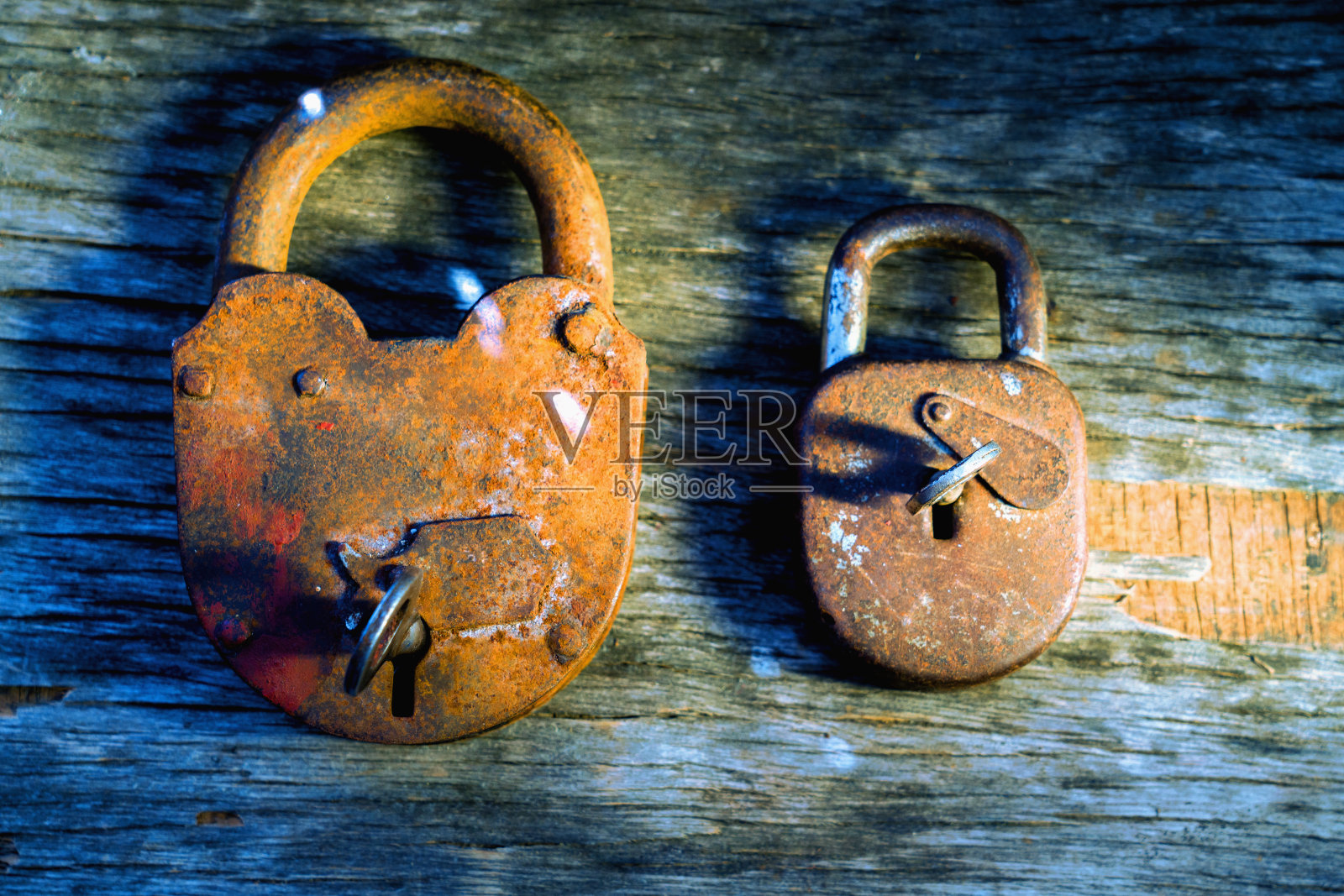 过时的安全系统及其强化概念。关闭两个可靠的金属锁不同大小的木制背景。照片摄影图片