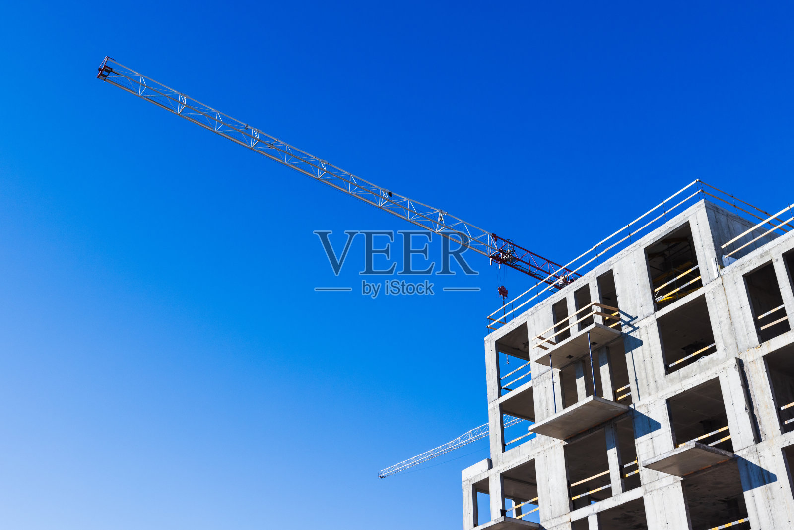 建筑起重机在现代混凝土房屋的骨架上工作照片摄影图片