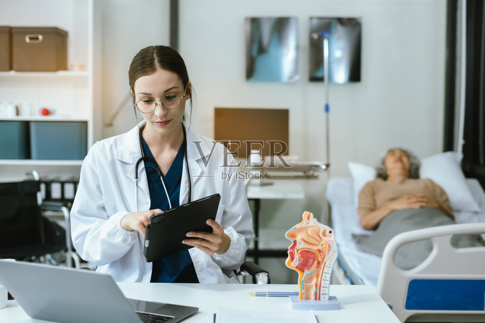 女医生在会诊时咨询老年患者填写表格，在门诊预约时与老年患者交谈填写医疗文件。照片摄影图片