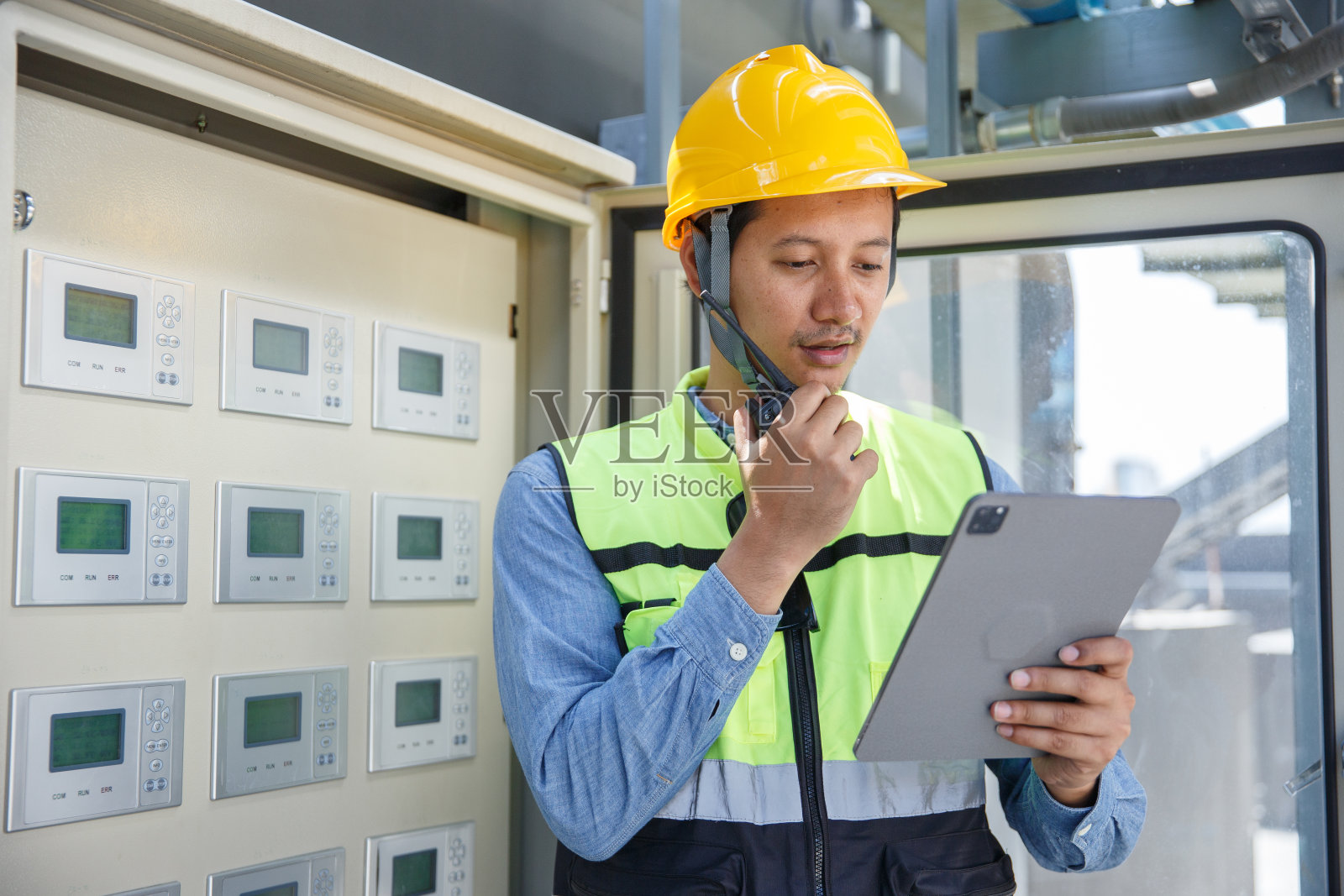 操作层员工工程师用对讲机向主管汇报在屋顶建筑施工现场检查控制系统大型空调的情况。暖通空调的技术员。照片摄影图片