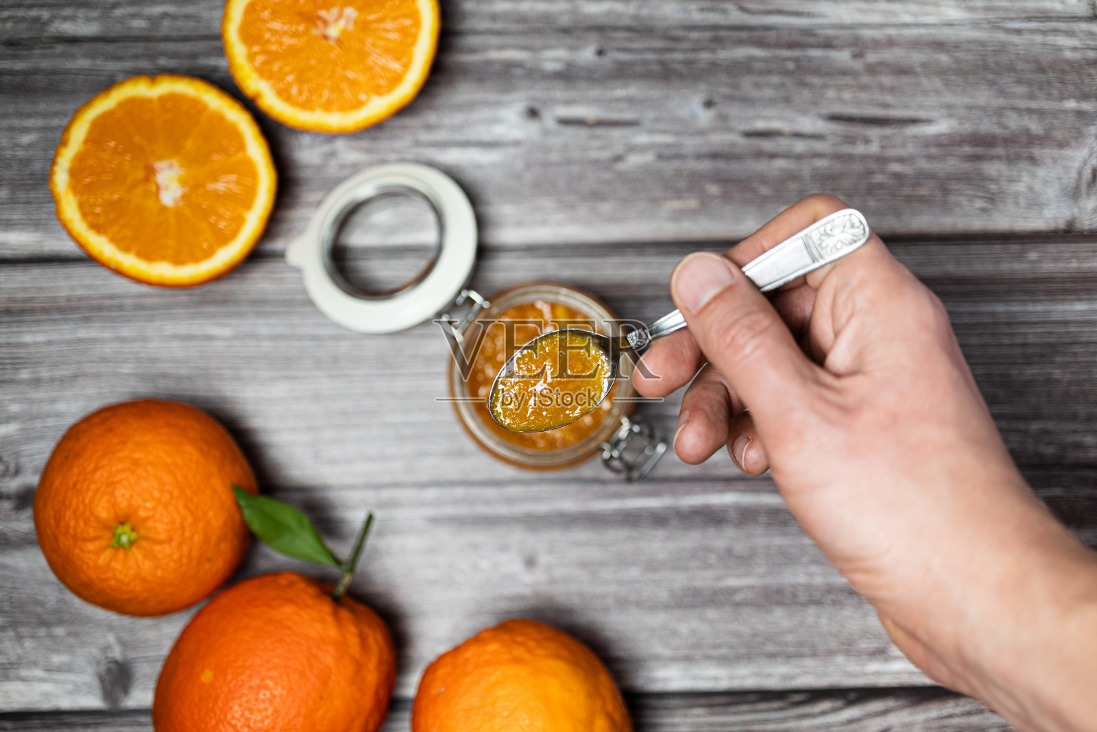 拿着一茶匙橘子酱的男人。美味的自制橙酱，健康的早餐。照片摄影图片