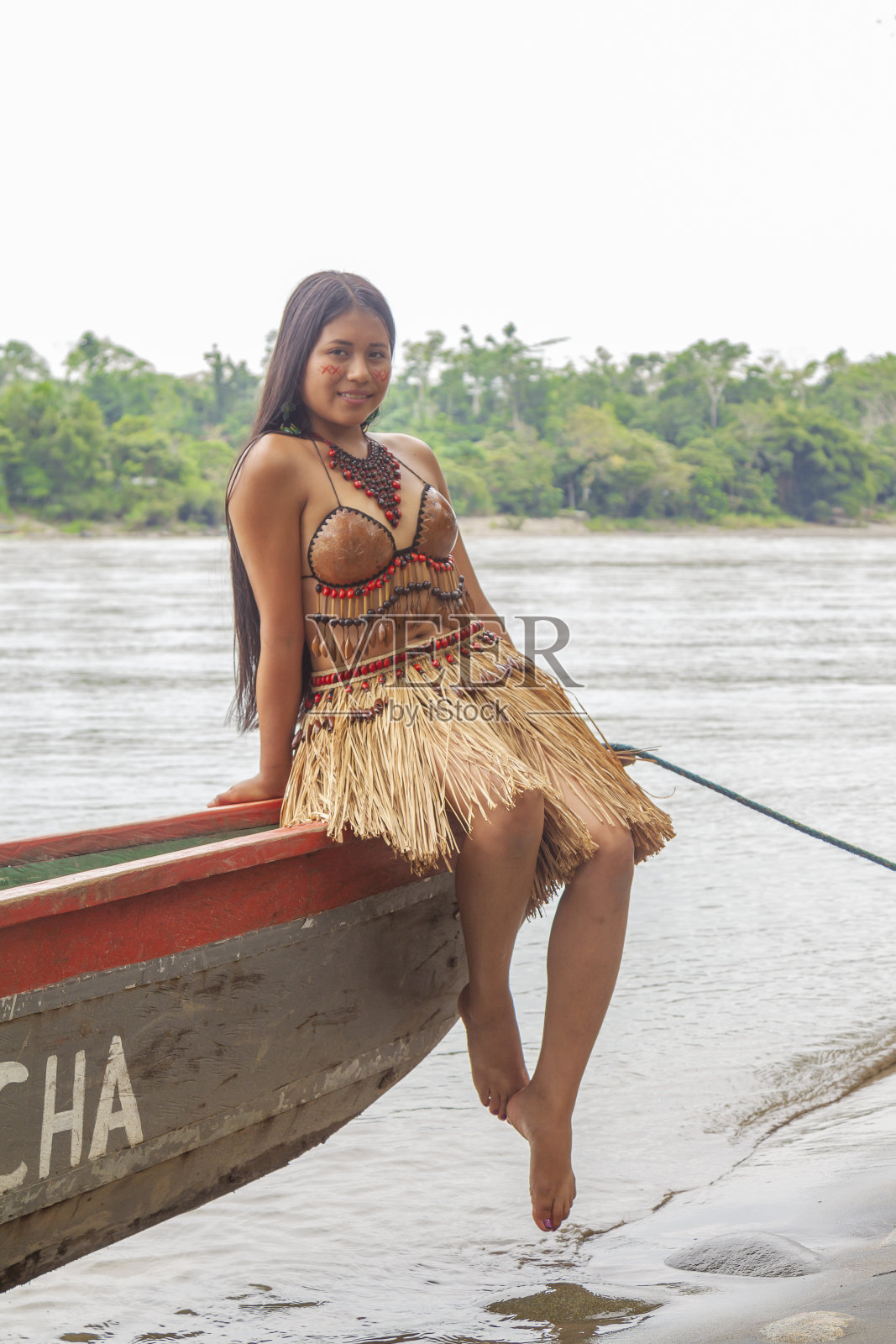一位年轻美丽的土著女性肖像，穿着部落的传统服装，在村庄里拍摄，背景是亚马逊河。基奇瓦部落。照片摄影图片