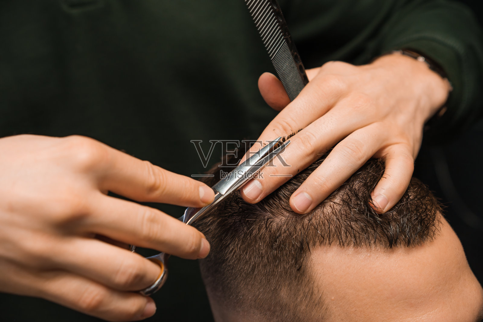 发型师在理发店用剪刀为顾客塑造深色头发。照片摄影图片