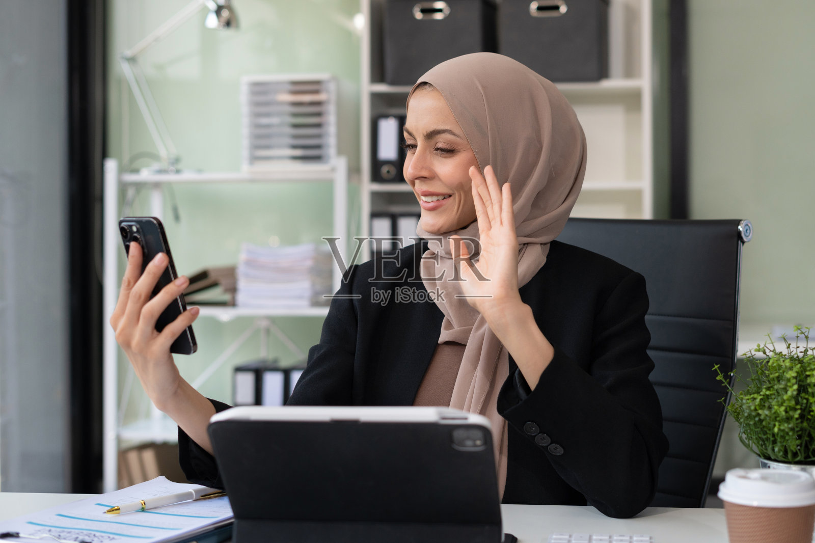 成功的商业女性在办公室使用笔记本电脑和智能手机。快乐的女人，企业家，小企业主在网上工作。照片摄影图片