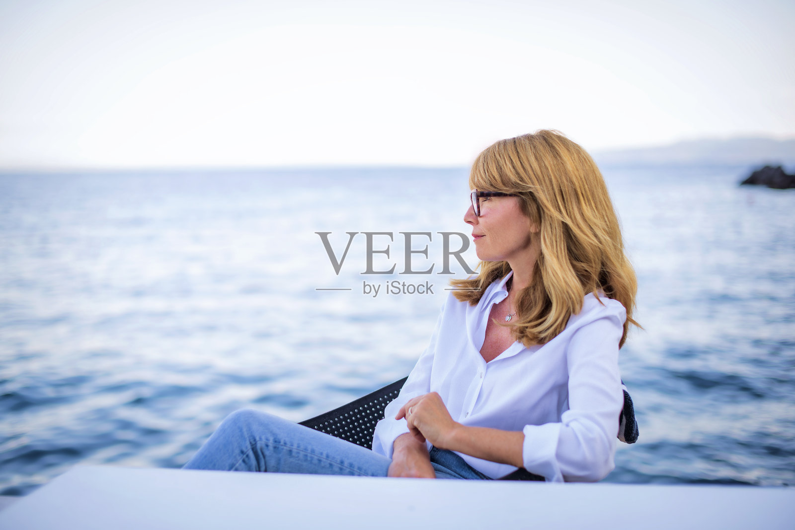 一个金发中年妇女在海边放松的画像照片摄影图片