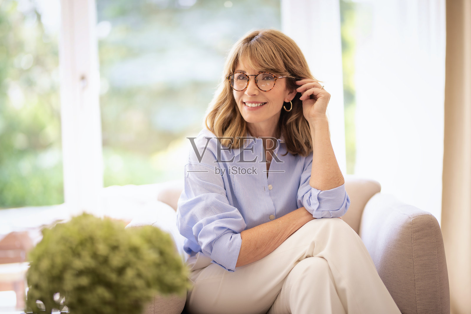 一个金发美女坐在家里的扶手椅上照片摄影图片