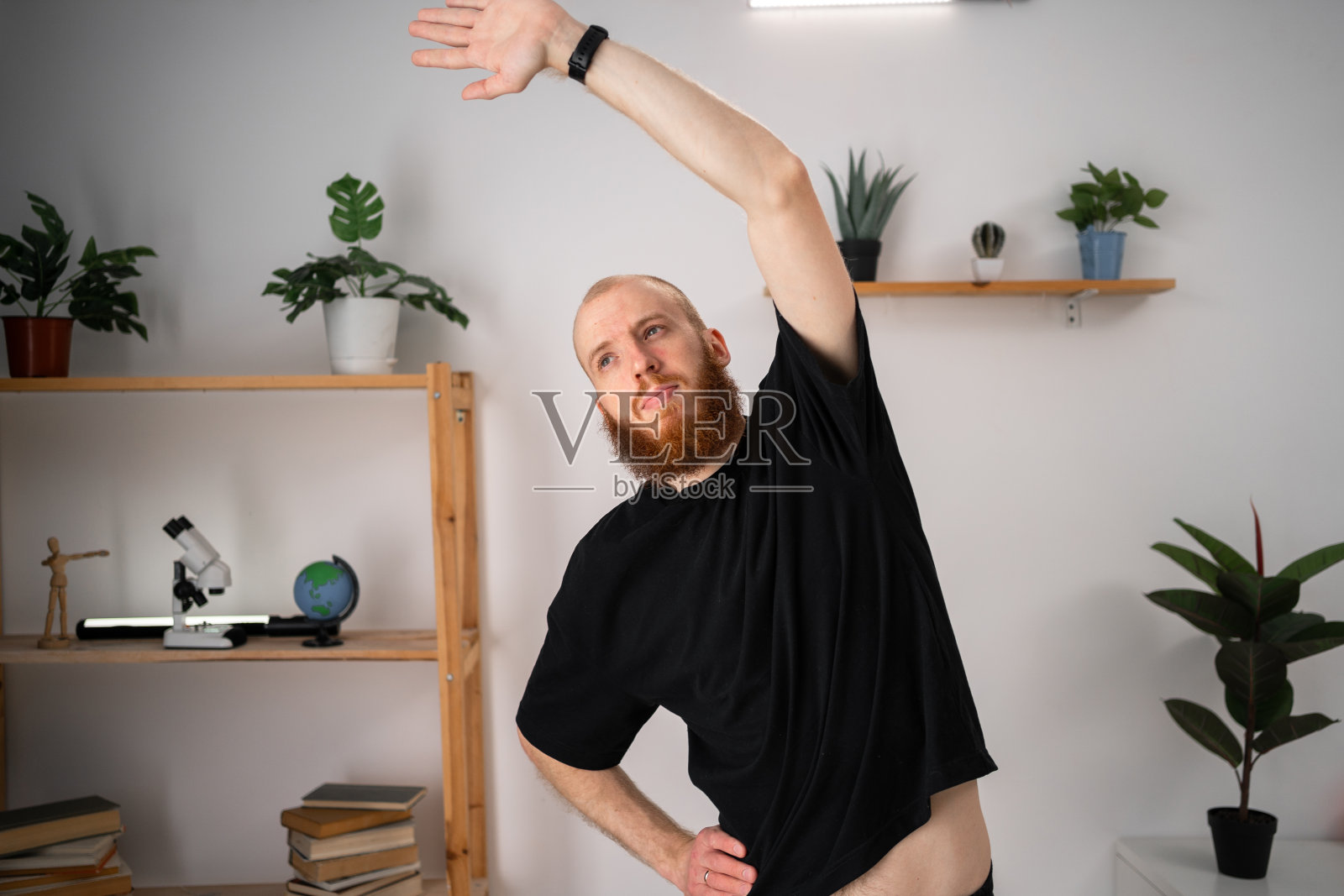 长着健壮胡子的男人在家里做运动，弯着腰，抄写空间。男性家政培训，健身照片摄影图片