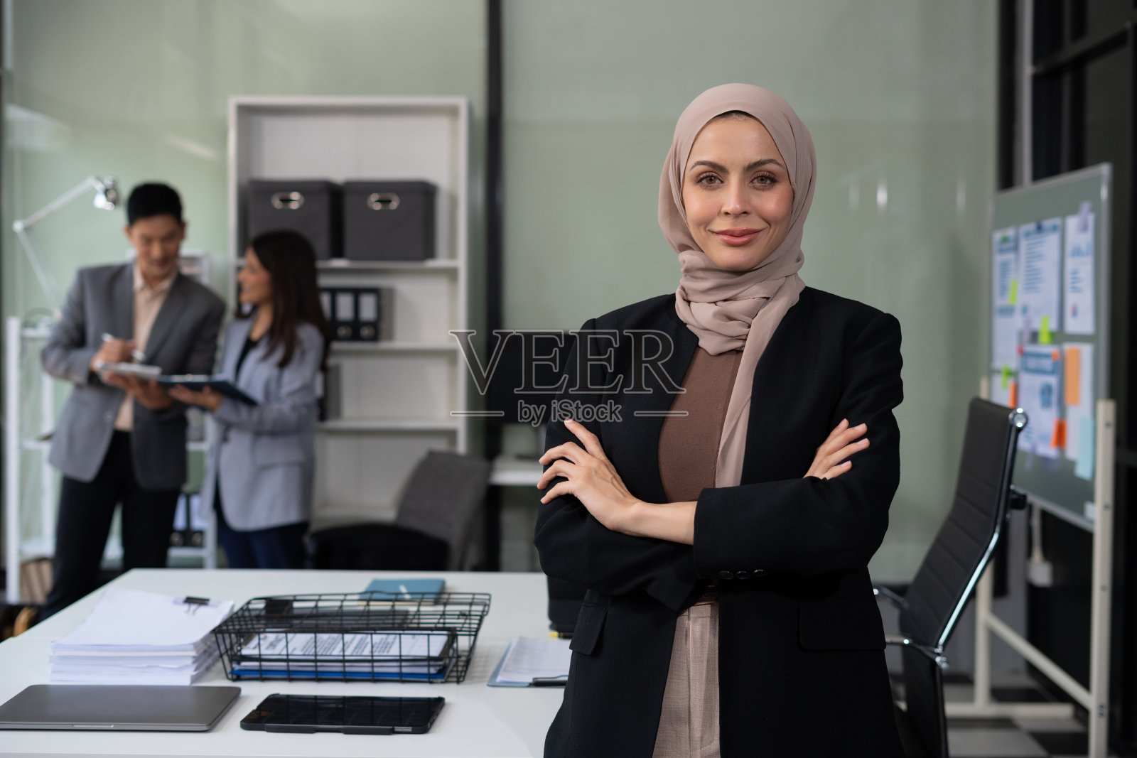 成功的商业女性在办公室使用笔记本电脑和智能手机。快乐的女人，企业家，小企业主在网上工作。照片摄影图片