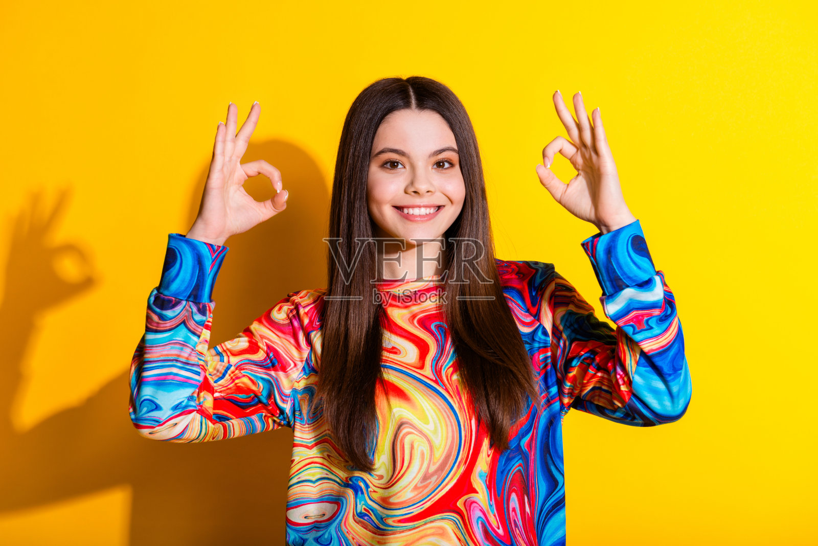 可爱的年轻女士的照片肖像，优雅的姿态，穿着时尚的彩色服装，孤立在黄色背景上照片摄影图片