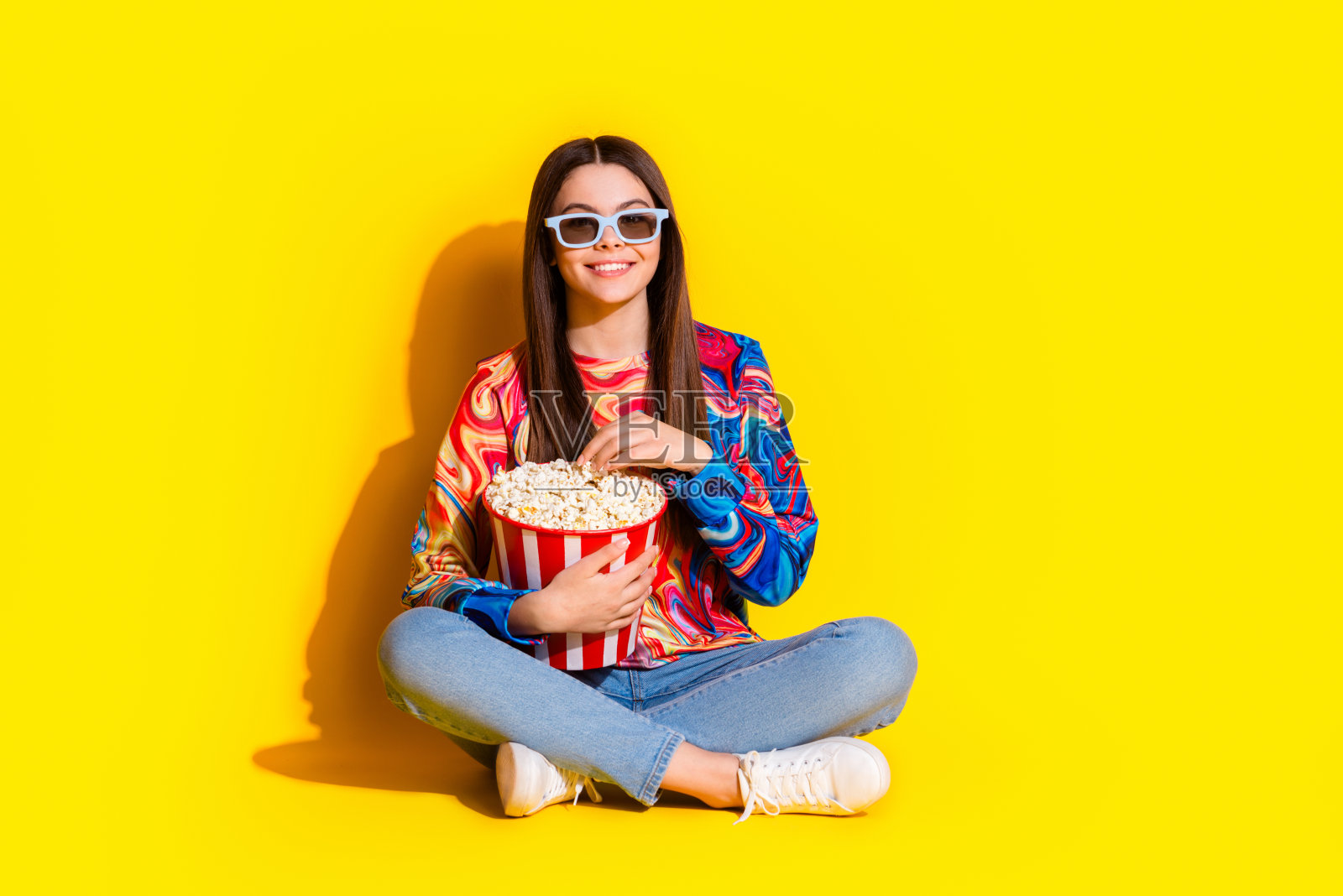 漂亮的年轻女孩的全尺寸照片看电影吃爆米花穿时髦的彩色服装孤立的黄色背景照片摄影图片