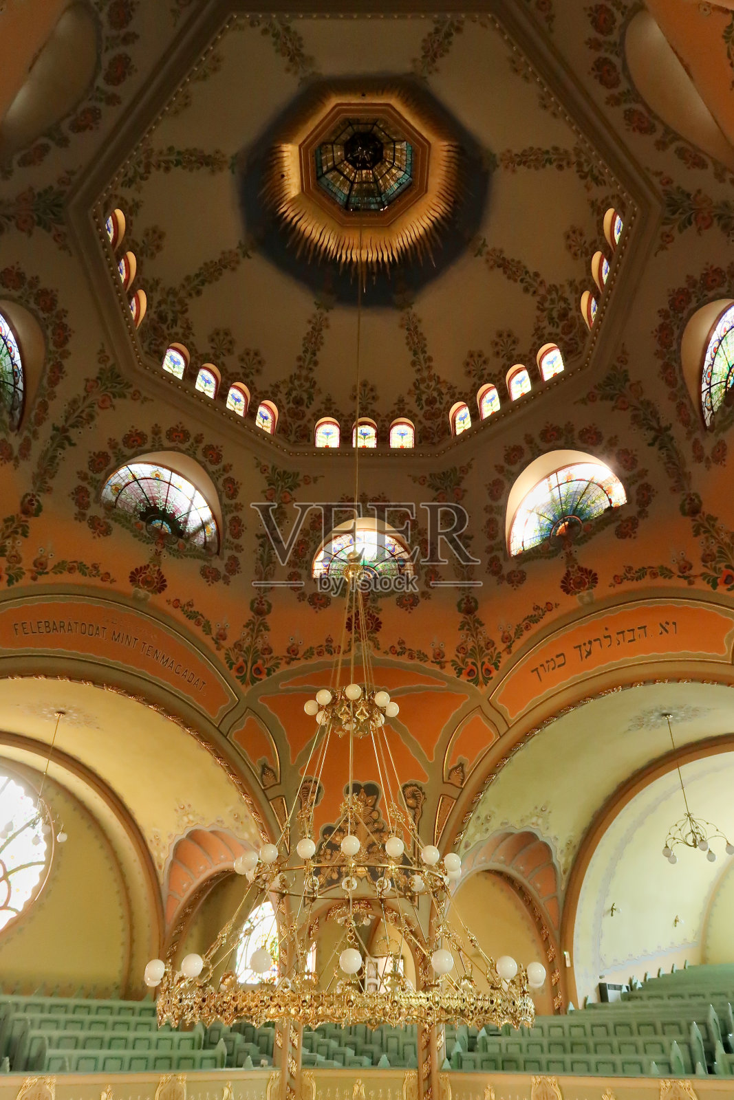 塞尔维亚苏博蒂察，在苏博蒂察的犹太教堂里，巨大的金色枝形吊灯悬挂在彩绘天花板、拱顶、圆顶上，灯光透过彩色玻璃窗照射进来照片摄影图片