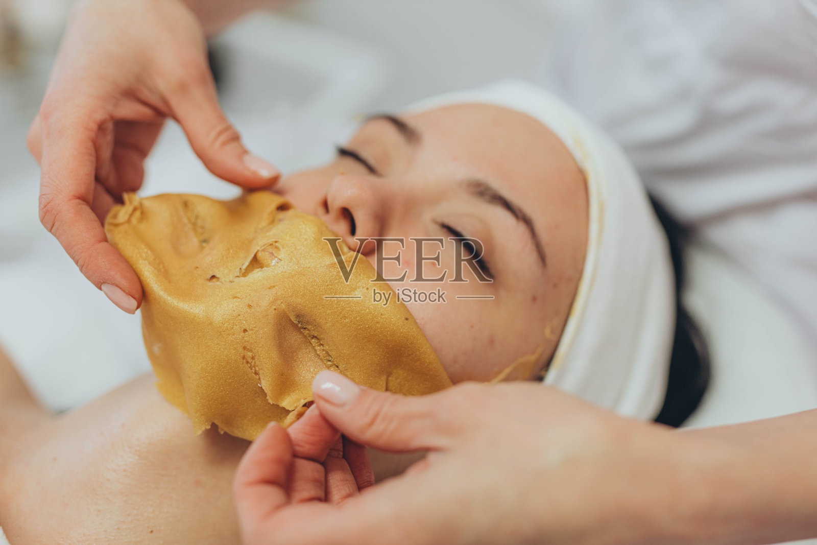 一个女孩在美容院做整容手术。海藻酸面具照片摄影图片