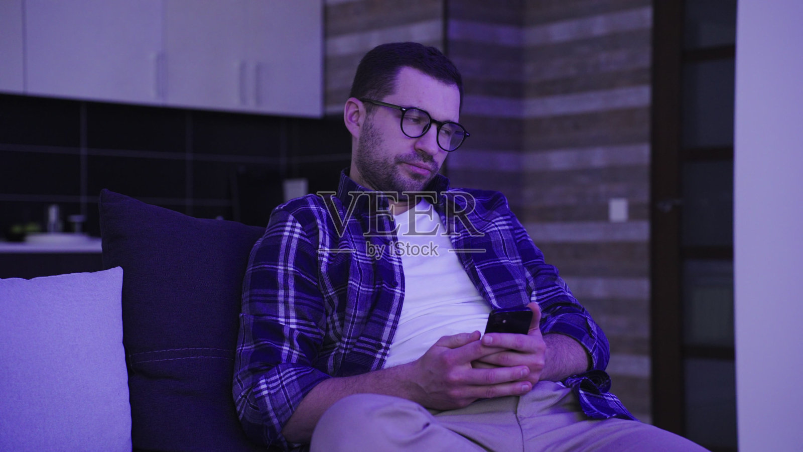 沮丧的年轻男子在家中看手机上的不良信息照片摄影图片
