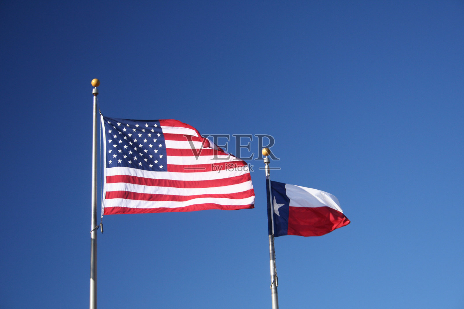 德克萨斯州和美国国旗在晴朗的蓝天下飘扬的特写照片摄影图片