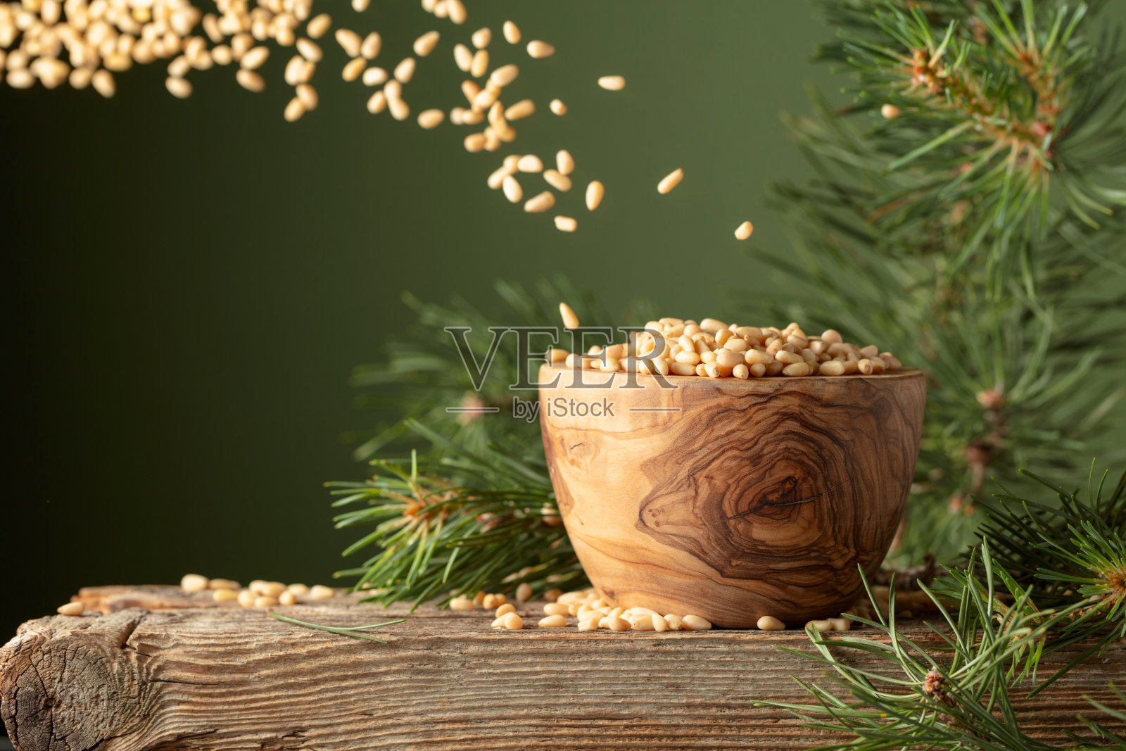 在深绿色的背景上飞舞着剥了皮的松子。照片摄影图片